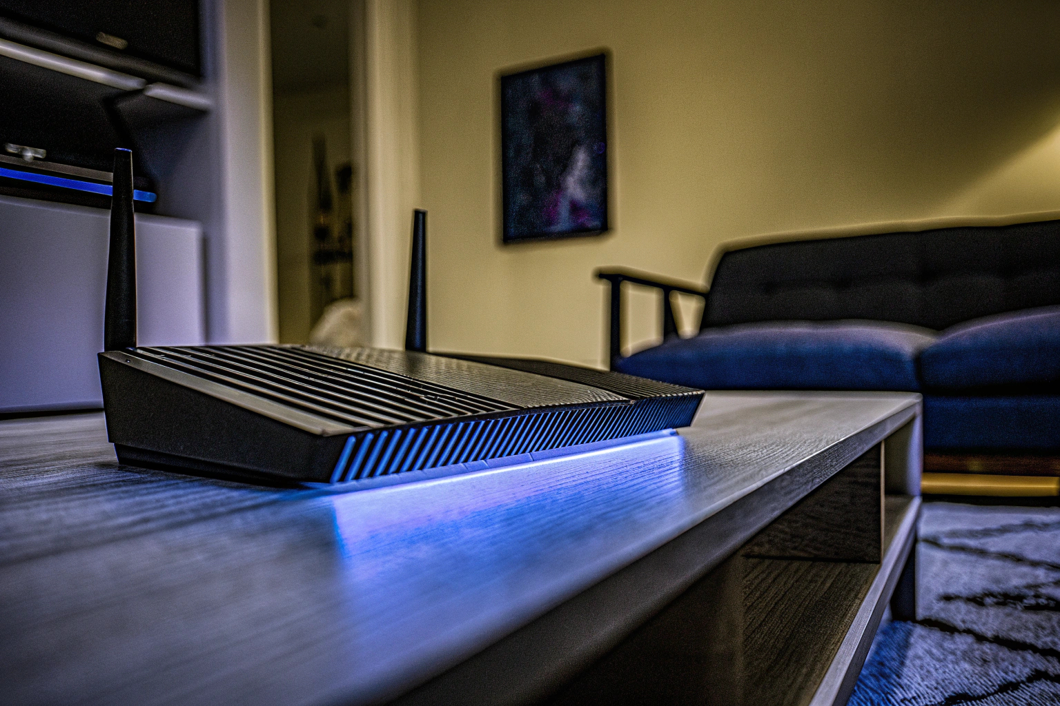 Detailaufnahme eines Asus RT-AX82U Gaming Routers mit Aura RGB Beleuchtung in einem modernen Wohnzimmer. Asus RT-AX82U Gaming Router mit Aura RGB
