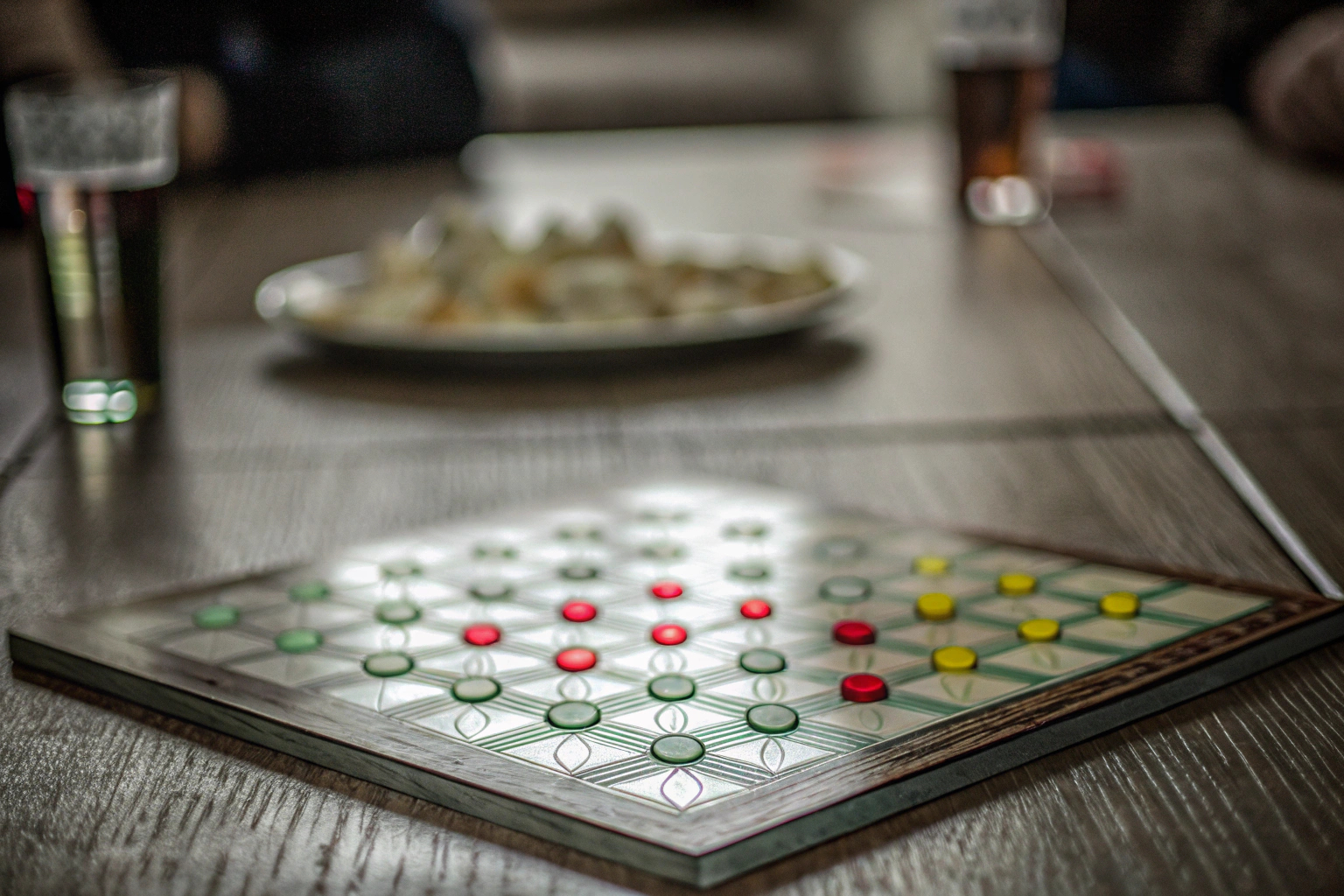 Detailaufnahme eines klassischen Brettspiels, das auf einem Tisch mit mehreren Spielern gespielt wird. Klassisches Brettspiel in Aktion