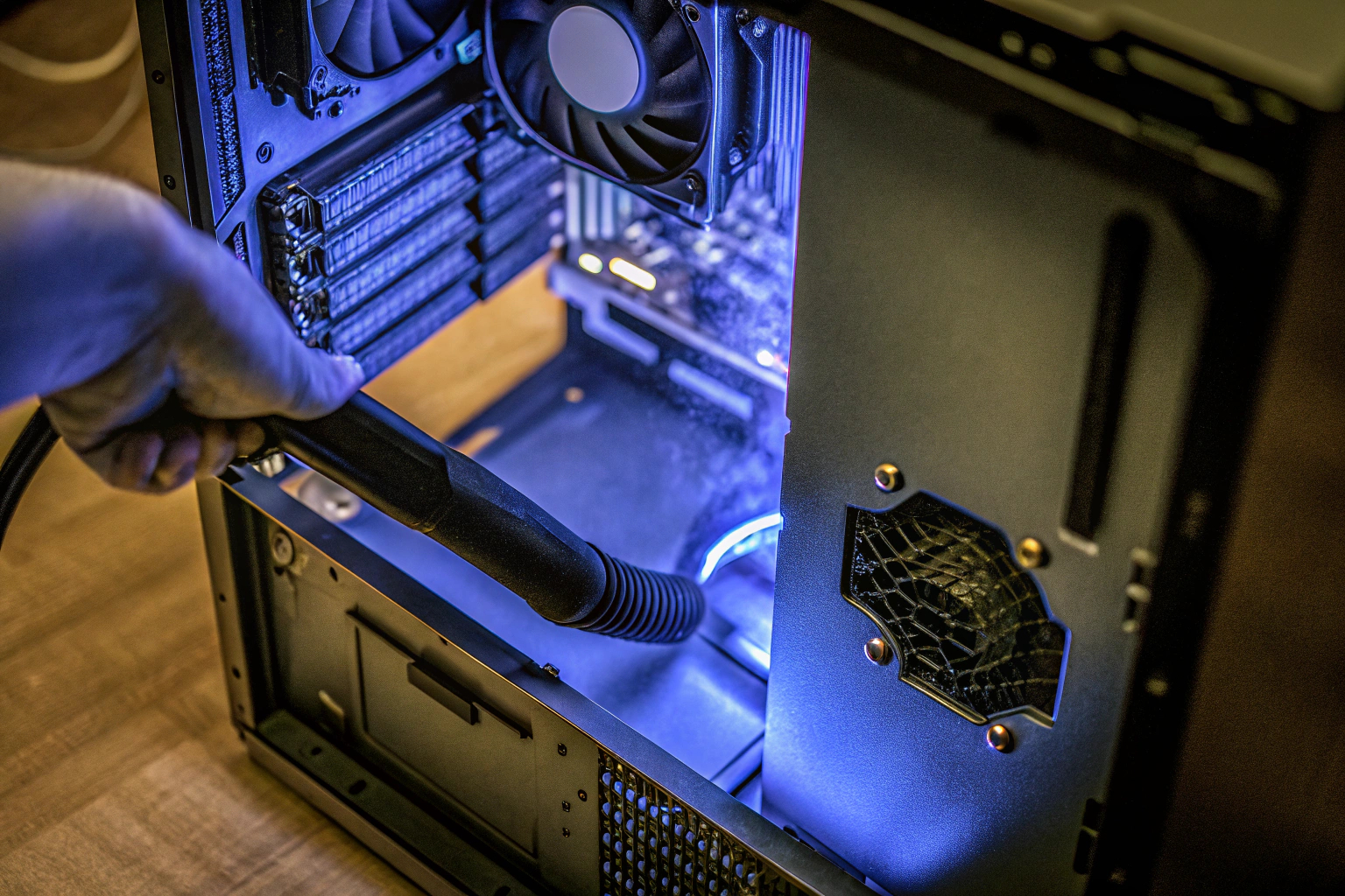 Ein Benutzer reinigt das Innere eines Computers mit einem elektrischen Staubgebläse. Reinigung eines Gaming-PCs