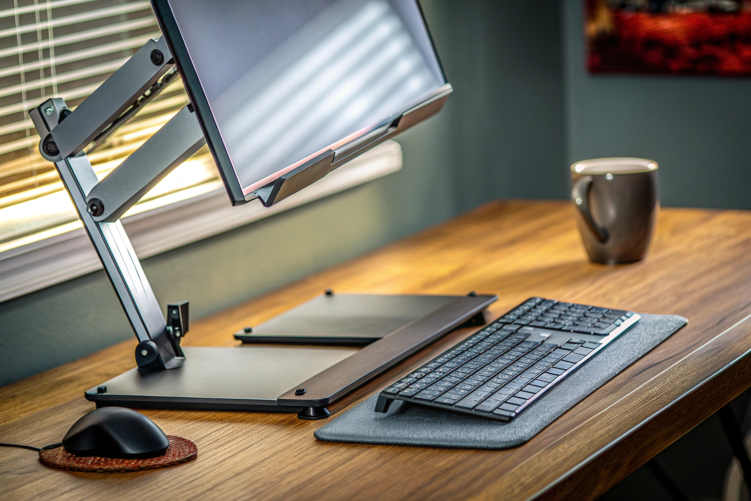 Ein Schreibtisch, auf dem ein Monitor auf einem höhenverstellbaren Ständer platziert ist, neben einer Tasse Kaffee. Höhenverstellbarer Monitorständer