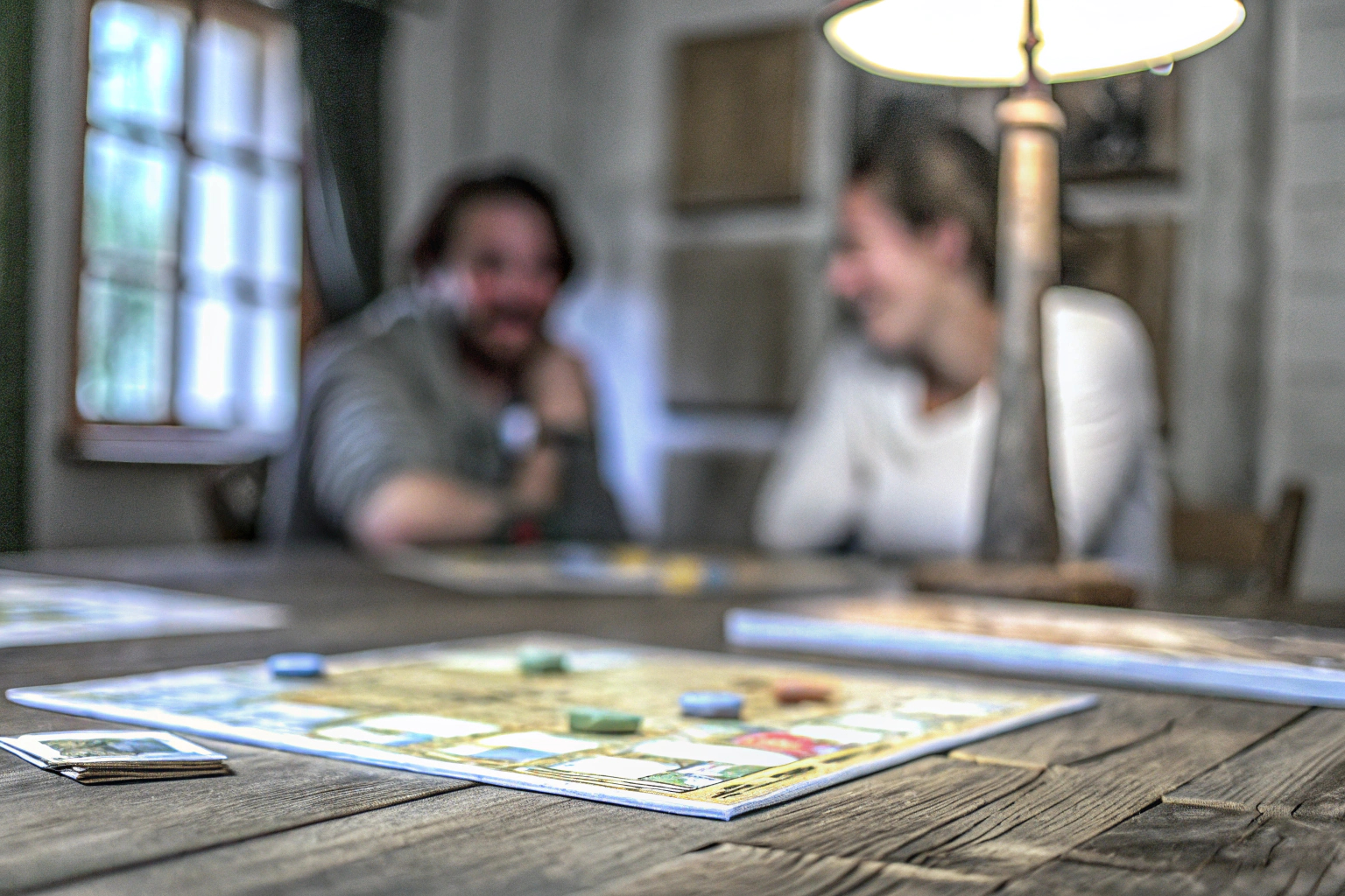 Ein Spieler, der in einem Indie-Brettspiel vertieft ist, während andere Spieler gespannt zuschauen. Indie-Brettspielrunde