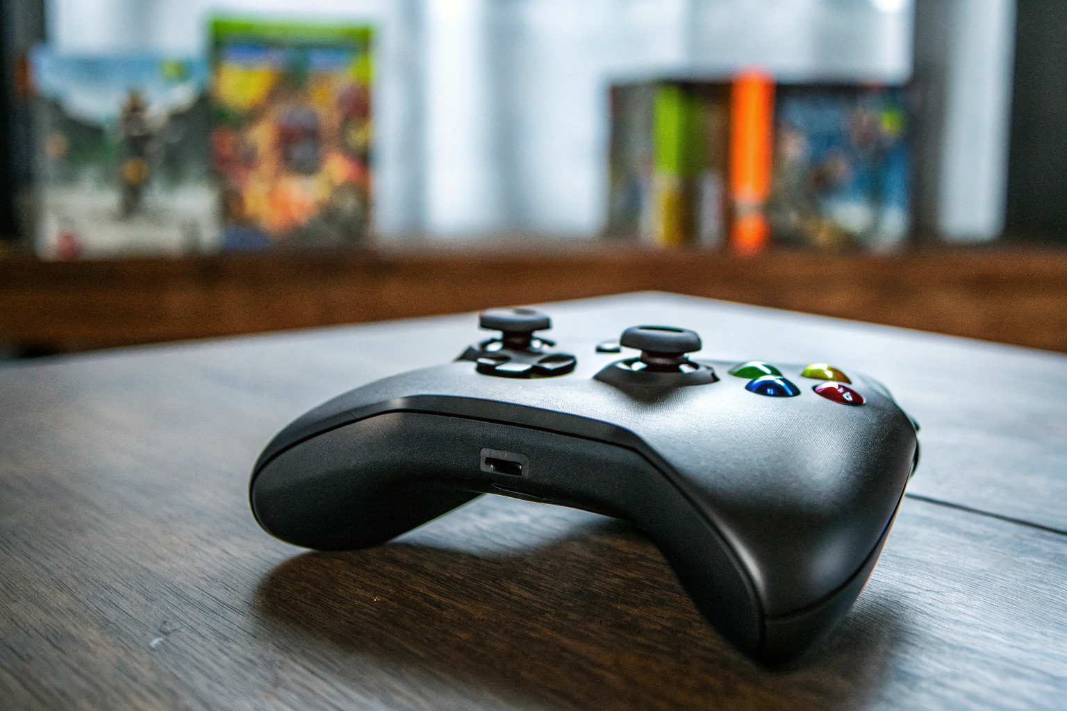 Ein Xbox-Controller auf einem Tisch, umgeben von verschiedenen Xbox-Spielen. Xbox-Controller und Spiele
