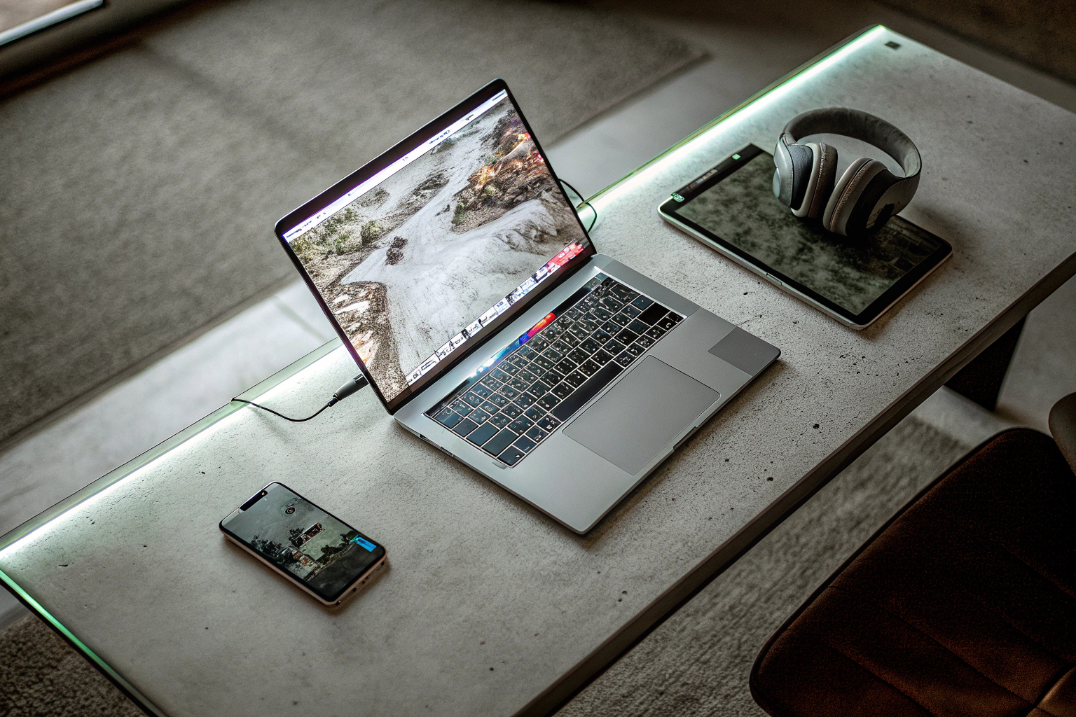 Eine Person, die auf einem modernen Laptop arbeitet und gleichzeitig ein mobiles Gerät verwendet, um die Vielseitigkeit von Sicherheitslösungen zu veranschaulichen. Multitasking mit Sicherheitssoftware