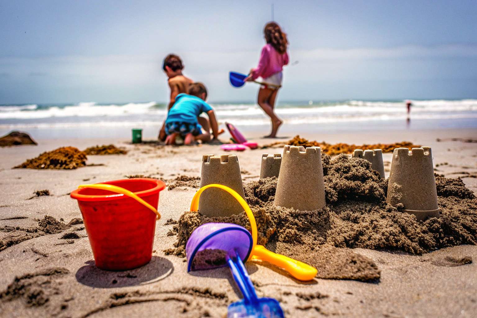 Kinder spielen mit einem Sandschlossbau-Set am Strand und gestalten fantasievolle Burgen. Kinder spielen mit Sandschlossbau-Set