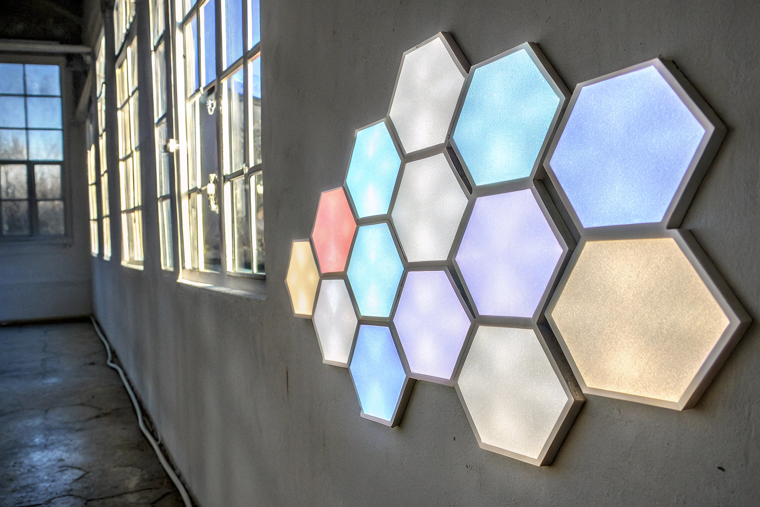 RGB Hexagon Panels an einer Wand, die in verschiedenen Farben leuchten und ein modernes Ambiente schaffen. RGB Hexagon Panels an einer Wand