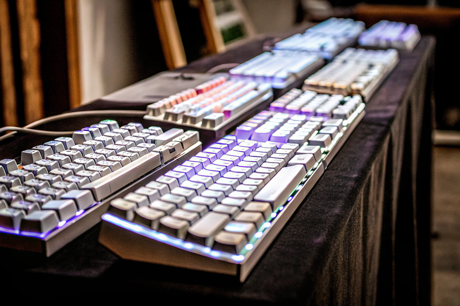 Verschiedene Gaming-Tastaturen mit RGB-Beleuchtung und unterschiedlichen Layouts. RGB Gaming-Tastaturen auf einem Schreibtisch